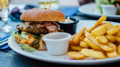 selective focus photography of burger patty, mayonnaise, and French fries served on platter